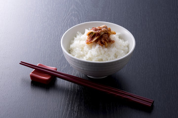 黒木目背景の白菜のキムチとごはんと箸