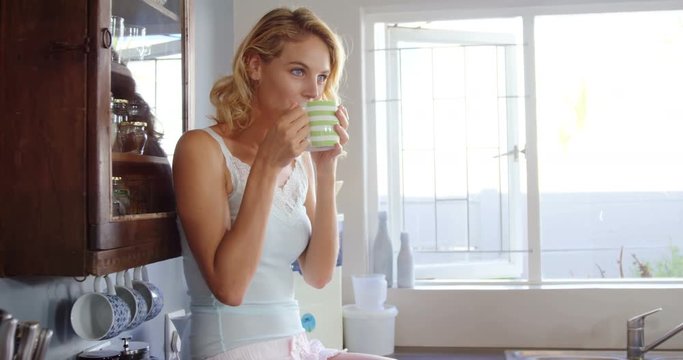 Cute blonde having coffee in kitchen