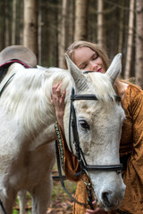 Blonde Frau in Mittelalter-Gewand umarmt ihr  Pferd