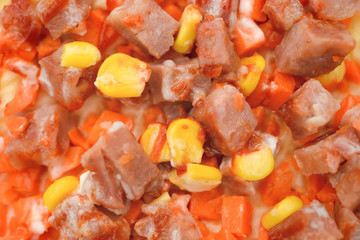 top of a pizza with meat maize and carrot close up