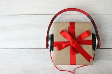 full-size wired headphones dressed in a box with a bow on white wooden background