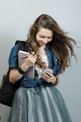 Young woman holding book and chatting by mobile