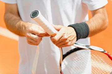 Zelfklevend Fotobehang Putting new grip tape on tennis racket © Microgen