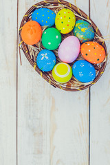 Easter eggs painted in pastel colors on white wooden background.