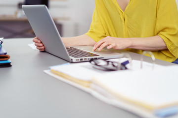 frau sitzt am schreibtisch und arbeitet am laptop