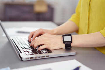 frau arbeitet am laptop und trägt eine smartwatch