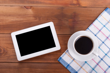 Tablet computer and a cup of coffee at the kitchen table.
