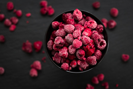 Frozen Raspberries in Bowl, Covered with Ice on Dark Background