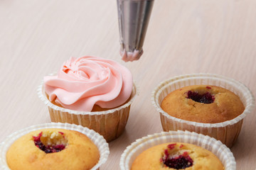 applying cream on cupcakes
