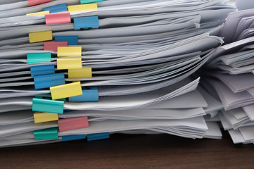 two piles of documents with colorful clips on desk stack up