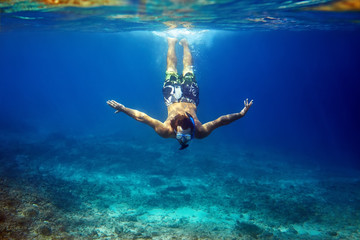 man with mask swimming underwater in tropical sea