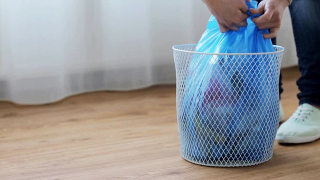 woman tying bag with garbage in waste bin