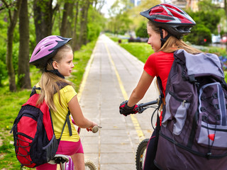 Naklejka premium Bikes bicyclist girl. Girls wearing bicycle helmet and glass with rucksack ciclyng bicycle. Girls children cycling on yellow bike lane. Bike share program save money and time at city street. Children