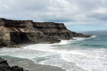Wave splashing over a rock on the beach of Puertito de los Molinos on Fuerteventura. Canary Island, Spain