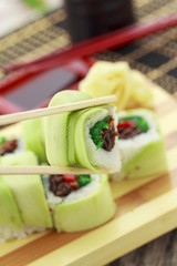 Sushi rolls with avocado on a wooden plate ( gete ).