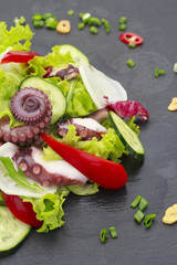 Salad with octopus baby corn and vegetables on a stone plate