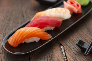 Sushi nigiri set on a black plate over wooden table