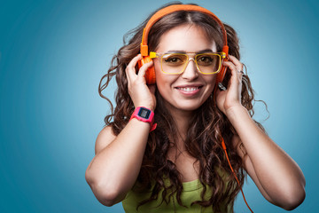 Happy girl in headphones and glasses listening to music, enjoying music and smiling.Closeup...
