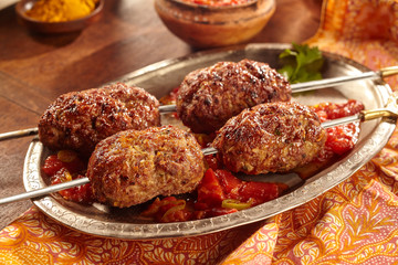 Two skewers of cooked meat on silver plate