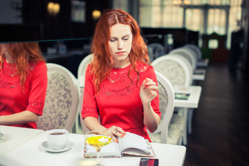 beautiful young girl in  cafe reading a book and drinking coffee. phone. student. business woman