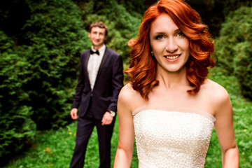 Redhead curly bride and groom behind her