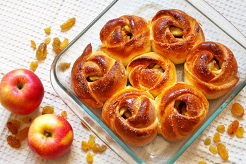 Freshly baked homemade buns with raisins and apples in a glass baking dish