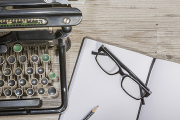 antique typewriter with blank book and reading glasses