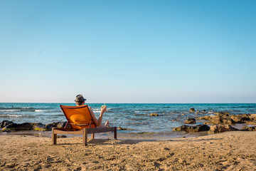 Young Man Relaxing on Chair Near the Sea and Drinking Cocktail Mojito, Free Space for Text