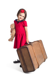 Beautiful little Girl smiling in red dress with suitcase and toy bear