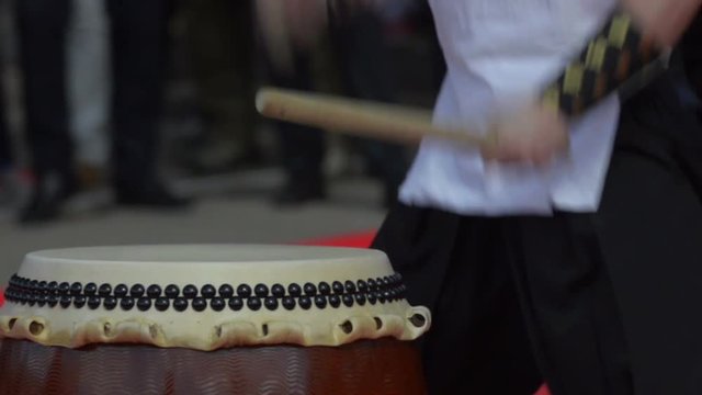 Japanese artist is drumming on traditional taiko drums. Drumsticks beating on a traditional drum