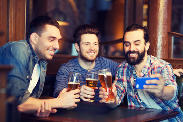 friends taking selfie and drinking beer at bar