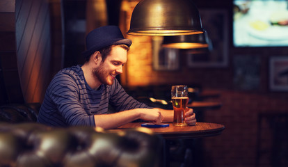 man with smartphone and beer texting at bar