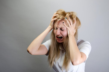 young woman screaming from pain and holding her head