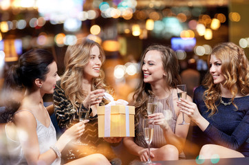 happy women with champagne and gift at night club