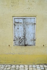 Fototapeta na wymiar Geschlossene Fensterläden aus Holz an einem sanierungsbedürftigen Gebäude