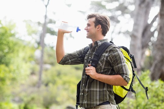 Young hiker drinking water while standing in forest