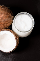 coconut oil and fresh coconuts on black stone