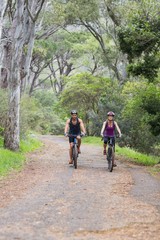 Man and woman riding bike in forest