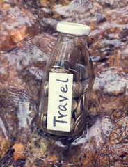 Saving coins in the glass jar for travel purpose. (Vintage style