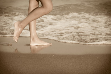 young woman legs on the beach at sunset