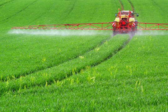 Traktor mit Feldspritze beim Ausbringen von Pflanzenschutzmittel