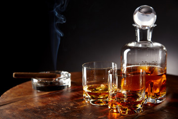 Decanter of alcohol by smoking cigar on a table