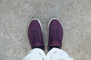 young girl with white jeans and red shoes standing on cement floor