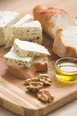 home made cheese and walnuts, olive oil and bread on a wooden board. brined curd white cheese with nuts on the table. Delicious food for breakfast or snack