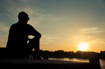 Man silhouette looking over the city at sunset