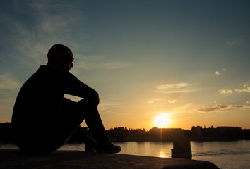 Man silhouette looking over the city at sunset
