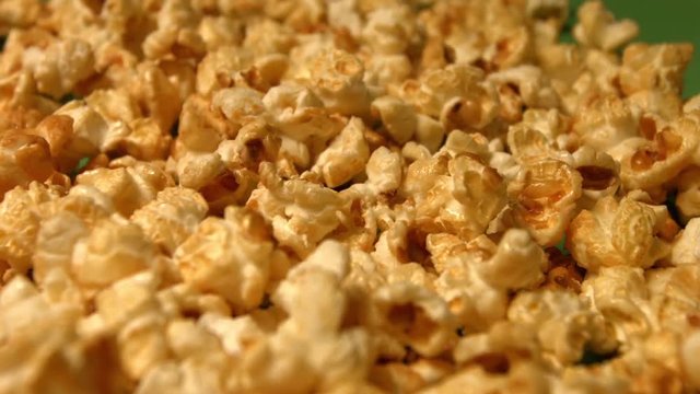 Popcorn on a green background. Slow motion. Close-up. Vertical pan. 3 Shots