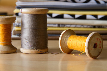 Modern patchwork fabrics in black, brown, white, yellow and grey on the wood table with yellow sewing spool