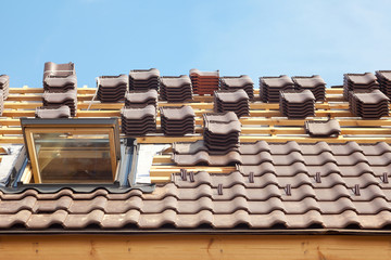 House under construction. Roofing tiles with open skylight