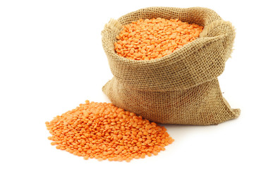 red lentils in a burlap bag on a white background